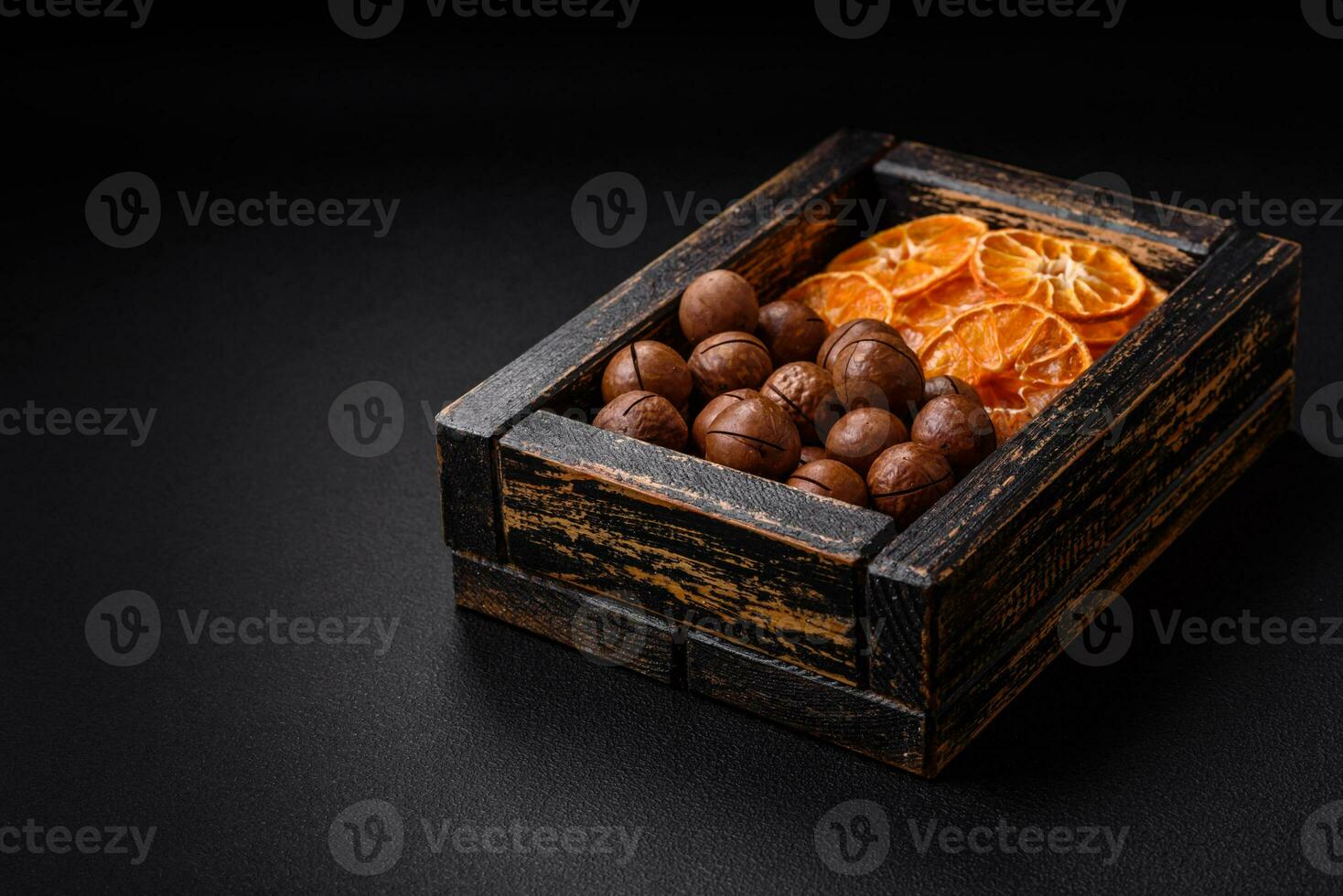 Delicious roasted macadamia nuts in shell on a dark textured background photo