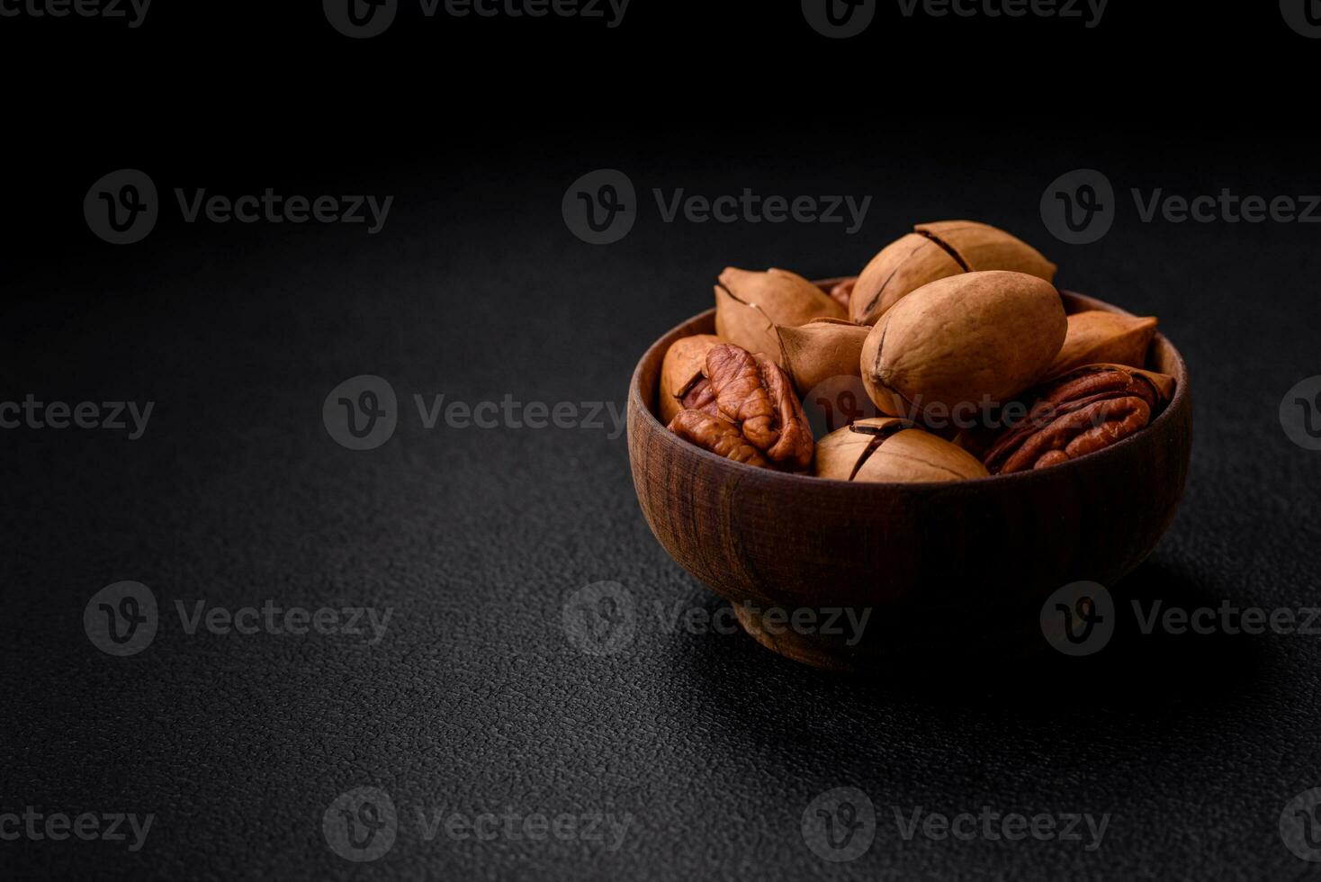 Pecan nuts in shell and peeled in a wooden round bowl photo