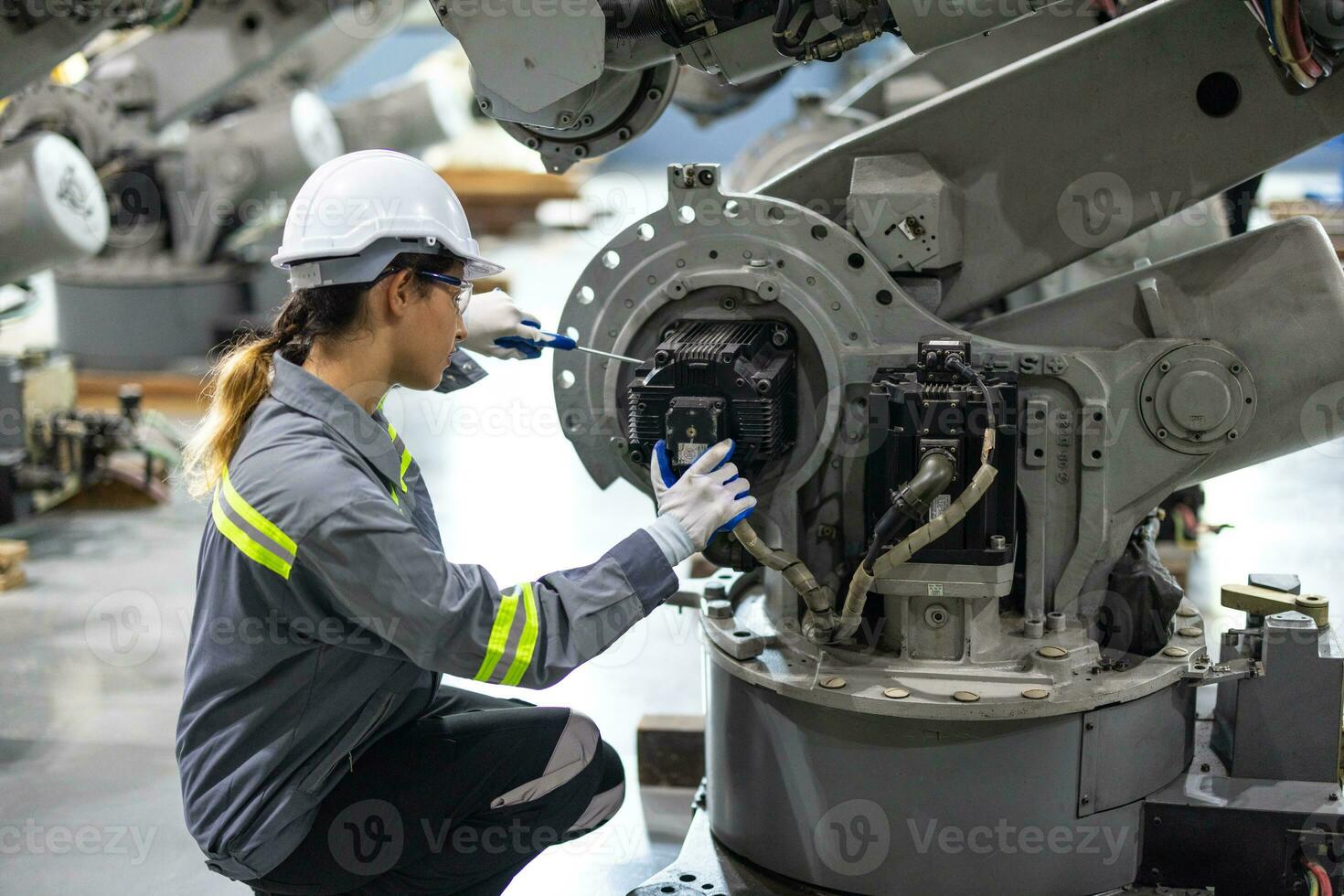 Robotic technicians tighten and loosen components with screwdriver and plier to perform safety maintenance. Measuring current, voltage, resistance, capacity, temperature with digital clamp meter. photo