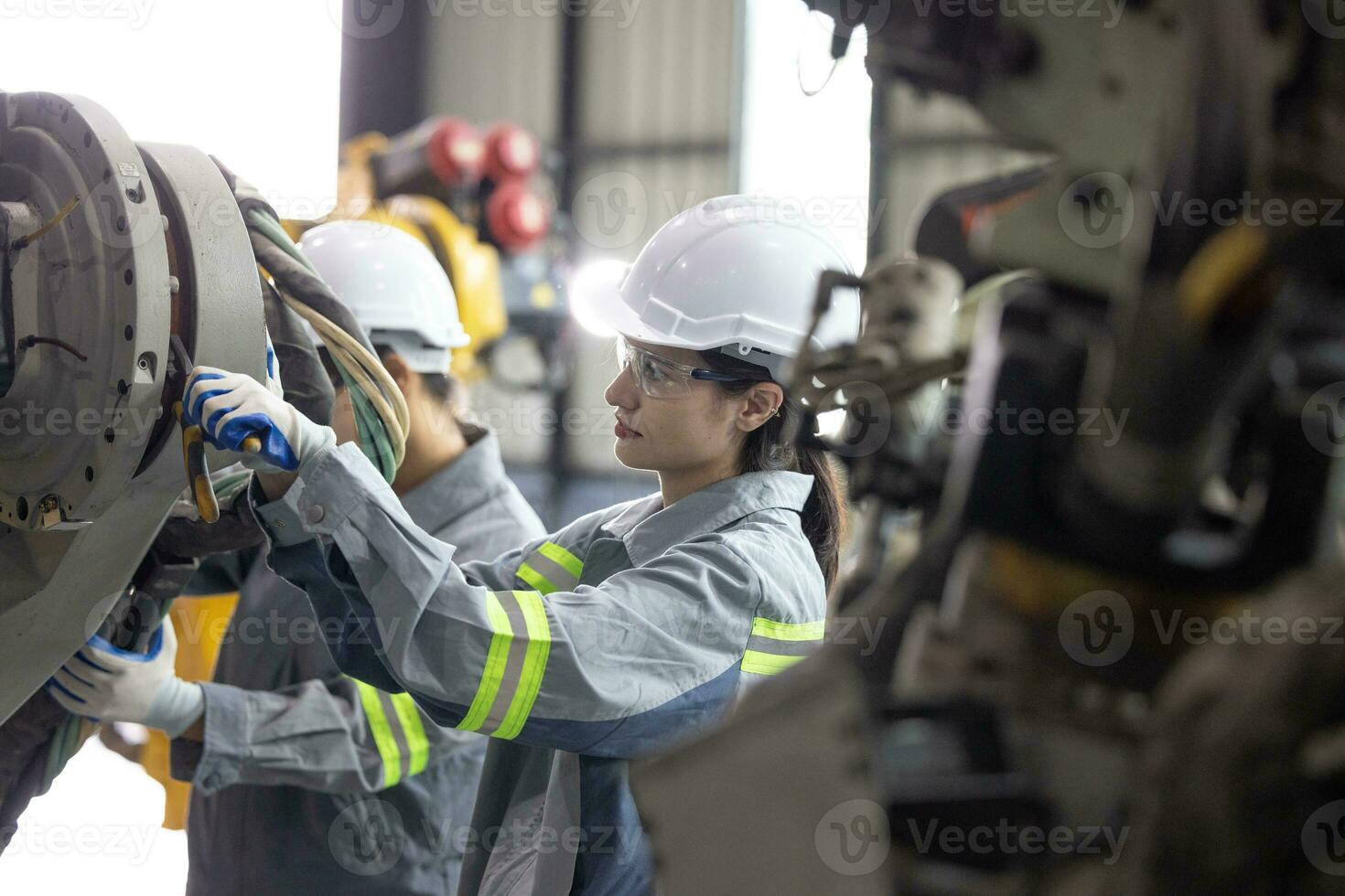 Robotic technicians tighten and loosen components with screwdriver and plier to perform safety maintenance. Measuring current, voltage, resistance, capacity, temperature with digital clamp meter. photo