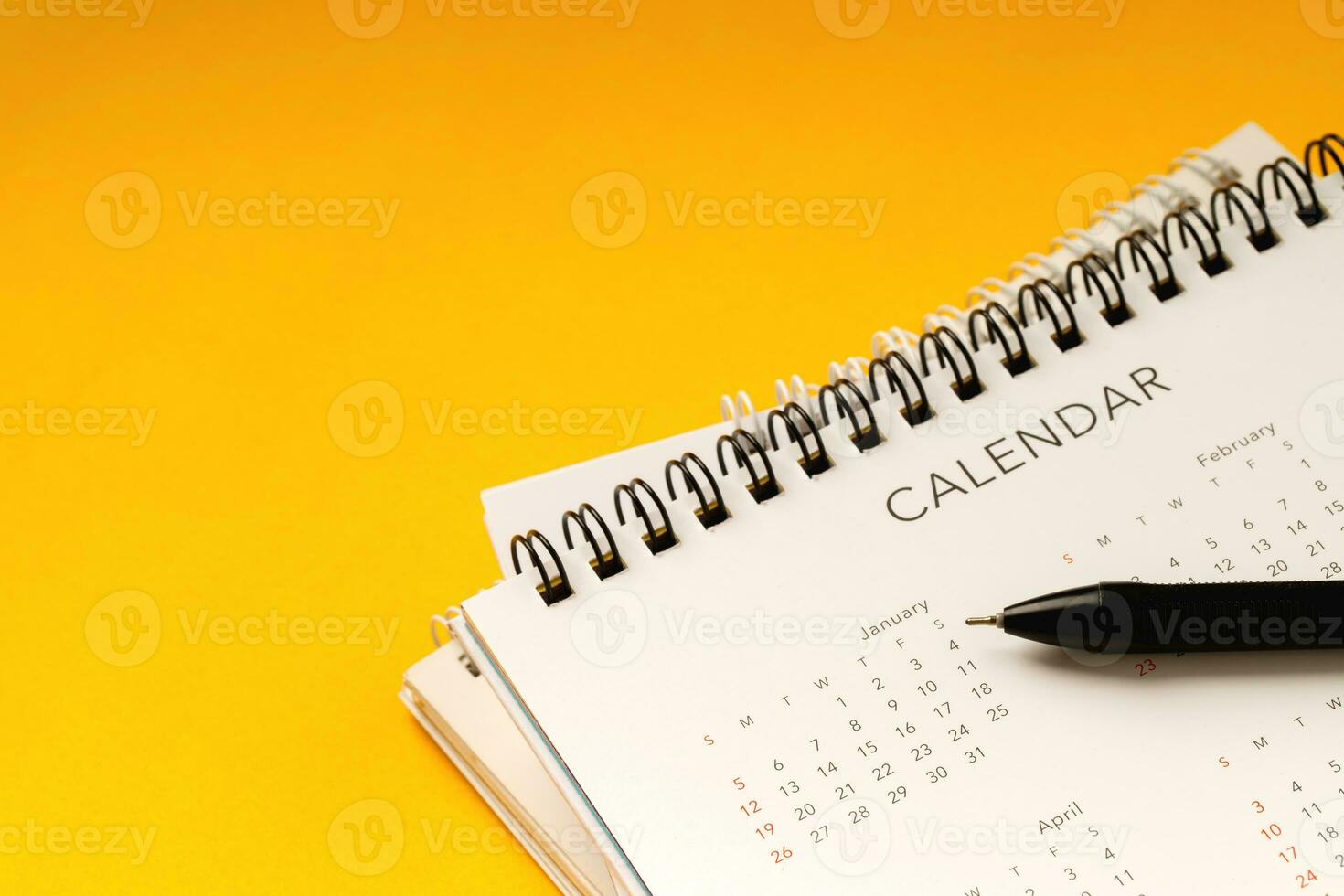 calendar month schedule to make appointment meeting or manage timetable each day lay and pen on yellow background for planning work and travel concept. photo