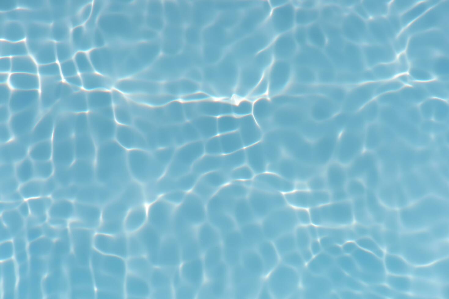 Blue water with ripples on the surface. Defocus blurred transparent blue colored clear calm water surface texture with splashes and bubbles. Water waves with shining pattern texture background. photo