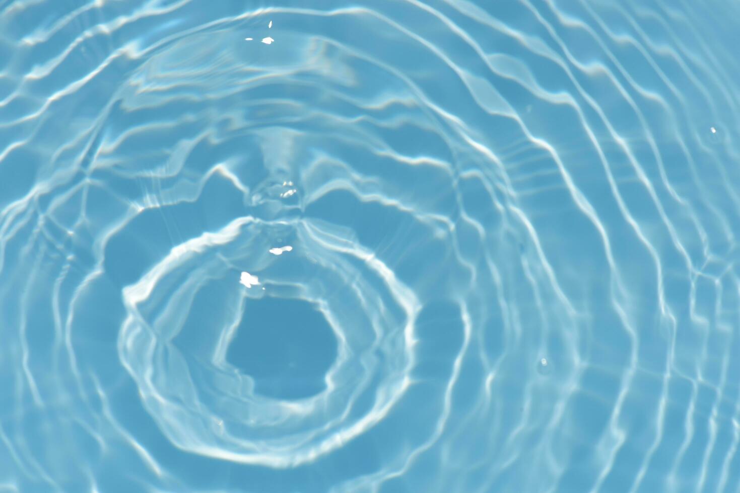 Blue water with ripples on the surface. Defocus blurred transparent blue colored clear calm water surface texture with splashes and bubbles. Water waves with shining pattern texture background. photo
