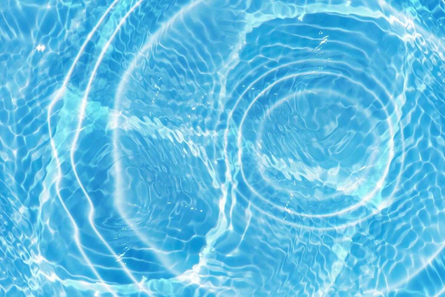 Blue water with ripples on the surface. Defocus blurred transparent blue colored clear calm water surface texture with splashes and bubbles. Water waves with shining pattern texture background. photo