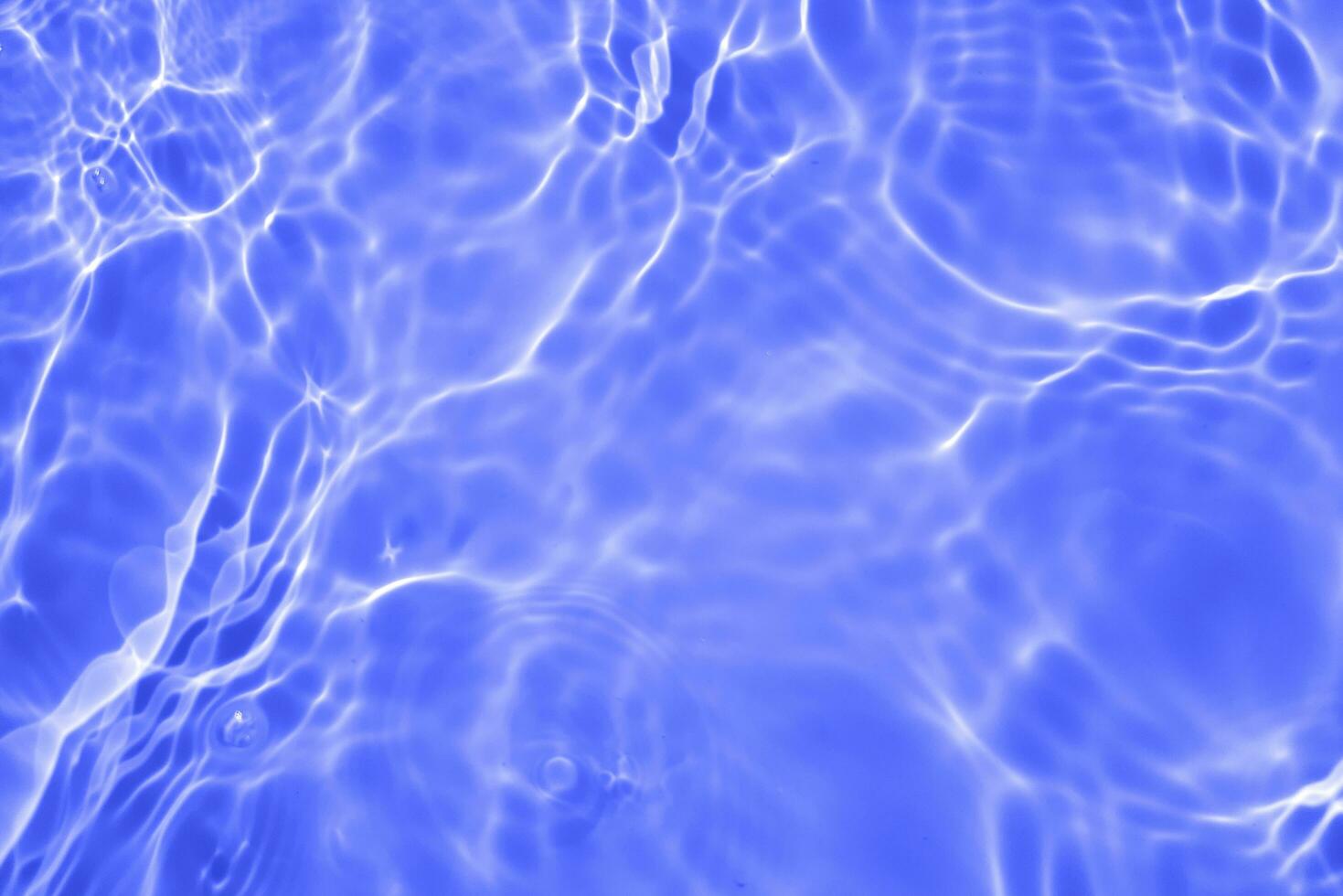 Blue water with ripples on the surface. Defocus blurred transparent blue colored clear calm water surface texture with splashes and bubbles. Water waves with shining pattern texture background. photo