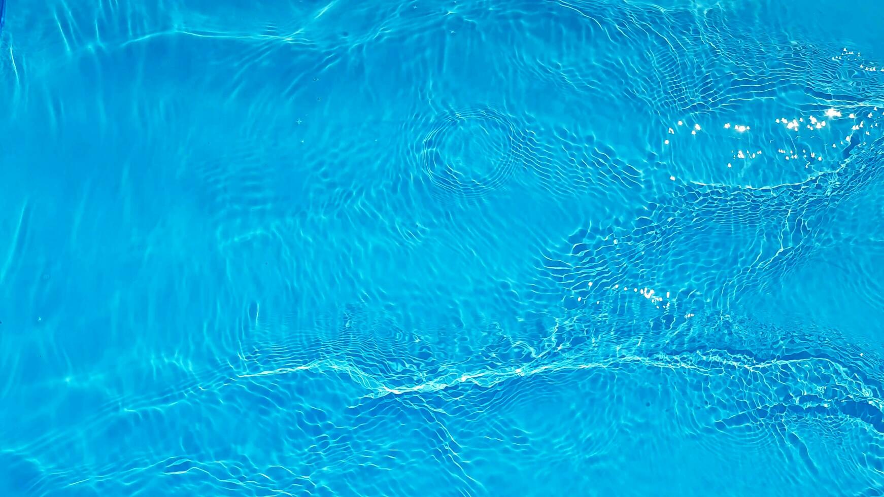 Blue water with ripples on the surface. Defocus blurred transparent blue colored clear calm water surface texture with splashes and bubbles. Water waves with shining pattern texture background. photo