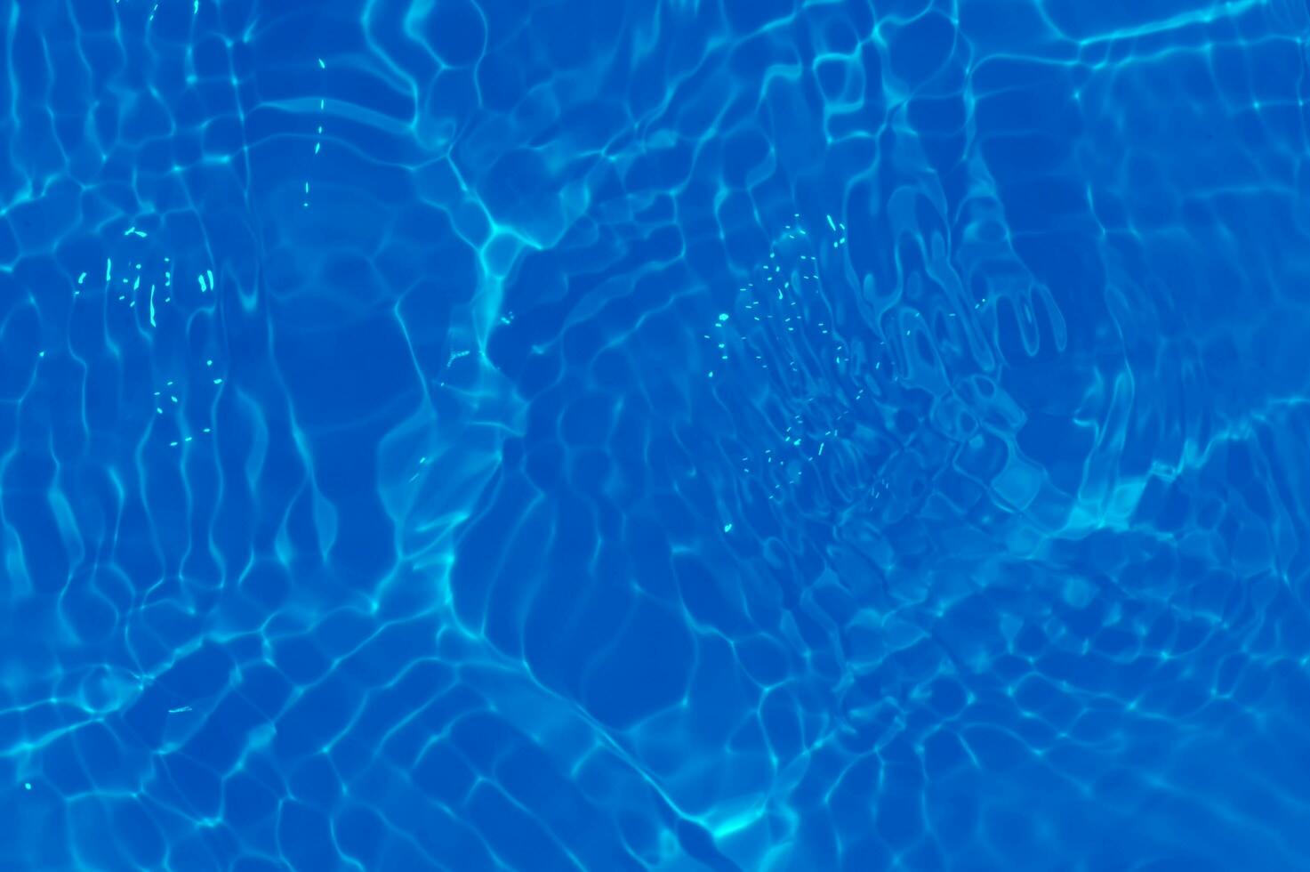 Blue water with ripples on the surface. Defocus blurred transparent blue colored clear calm water surface texture with splashes and bubbles. Water waves with shining pattern texture background. photo