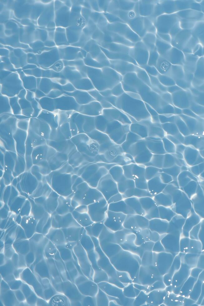 Blue water with ripples on the surface. Defocus blurred transparent blue colored clear calm water surface texture with splashes and bubbles. Water waves with shining pattern texture background. photo