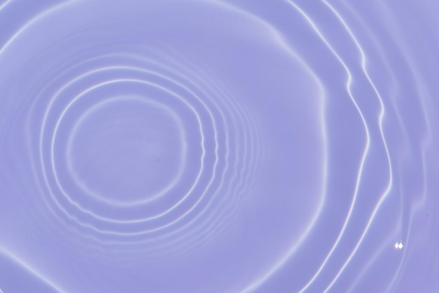 Purple water with ripples on the surface. Defocus blurred transparent pink colored clear calm water surface texture with splashes and bubbles. Water waves with shining pattern texture background. photo