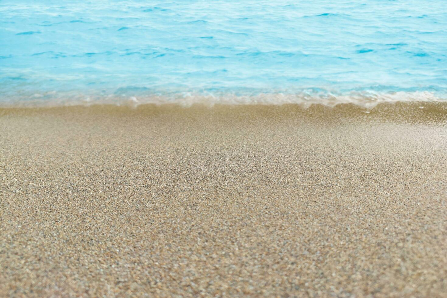Blue water with ripples on the surface with sand sea beach. Defocus blurred transparent blue water ripple surface texture with splashes and bubbles. Water wave with shining pattern texture background. photo