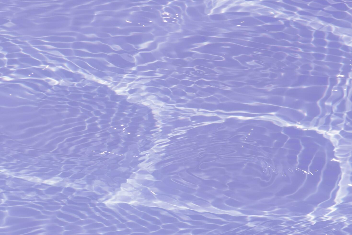 Purple water with ripples on the surface. Defocus blurred transparent pink colored clear calm water surface texture with splashes and bubbles. Water waves with shining pattern texture background. photo