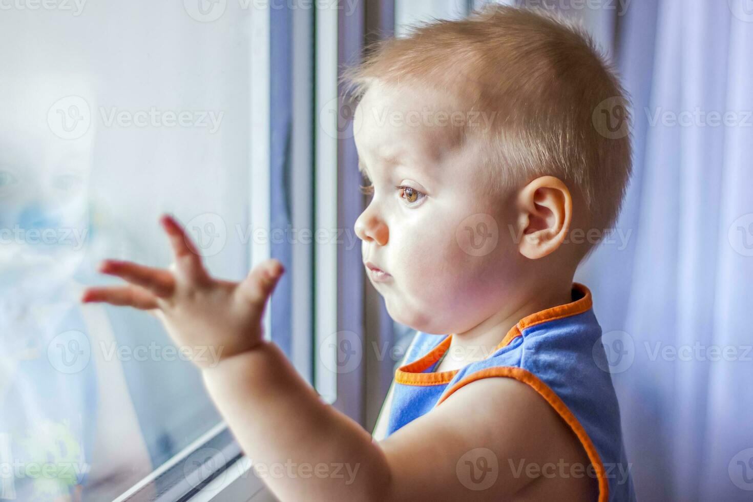 The child looks out the window. He really wants to walk. Because of the quarantine, everyone stays at home and doesn't go anywhere. photo