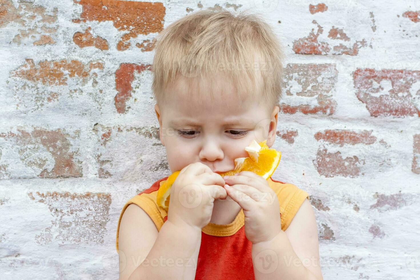 Portrait of child. Cute boy posing with an orange. The emotions of a child. photo