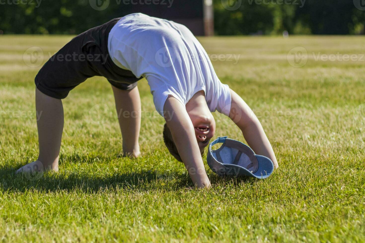 un alegre niño sonrisas con alegría. yo a.m contento a caminar y jugar en el césped en calentar soleado clima en el parque. el emociones de niños en el rostro. foto