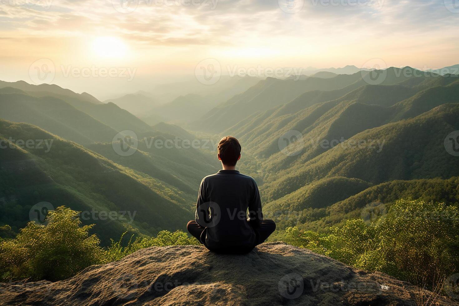 A person meditating on top of a hill, overlooking a vast landscape of mountains and forest. photo