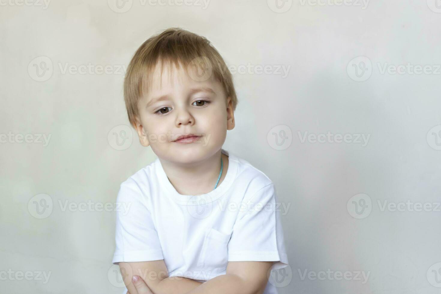 Portrait of a cute little boy in a white t-shirt. Children's emotions. Child on the background of the wall. Success, bright idea, creative ideas and concepts. photo