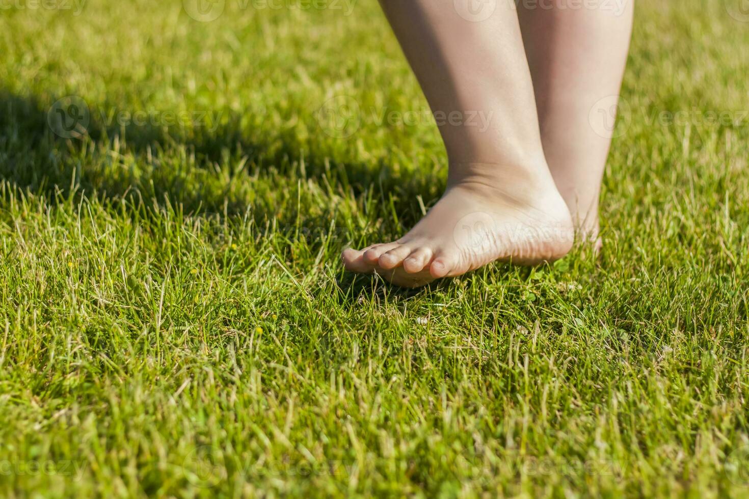 el niño desnudo pies en el césped. yo a.m contento a caminar y jugar en el césped en calentar soleado clima en el parque foto