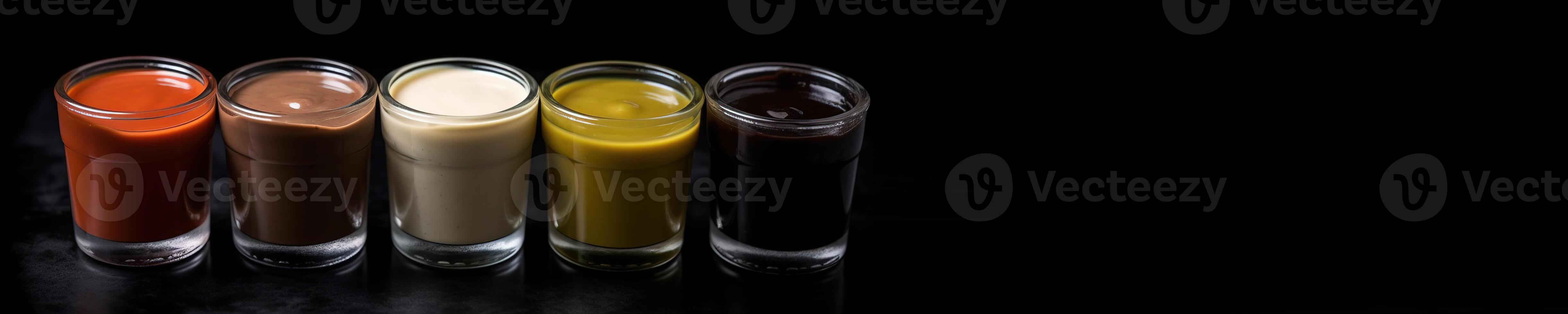 Various sauces, marinades and dressings in small bowls in a row, dark background. . photo