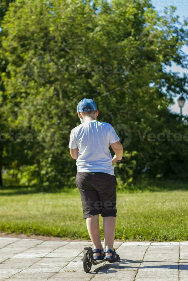 A schoolboy boy is traveling on a scooter. photo