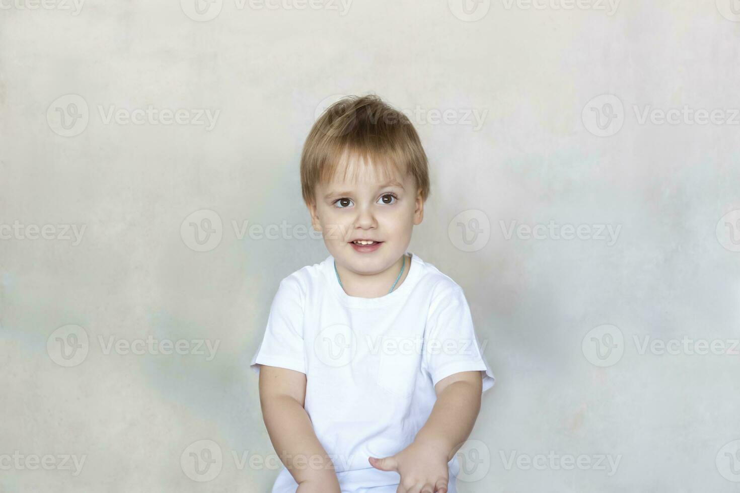 Portrait of a cute little boy in a white t-shirt. Children's emotions. Child on the background of the wall. Success, bright idea, creative ideas and concepts. photo