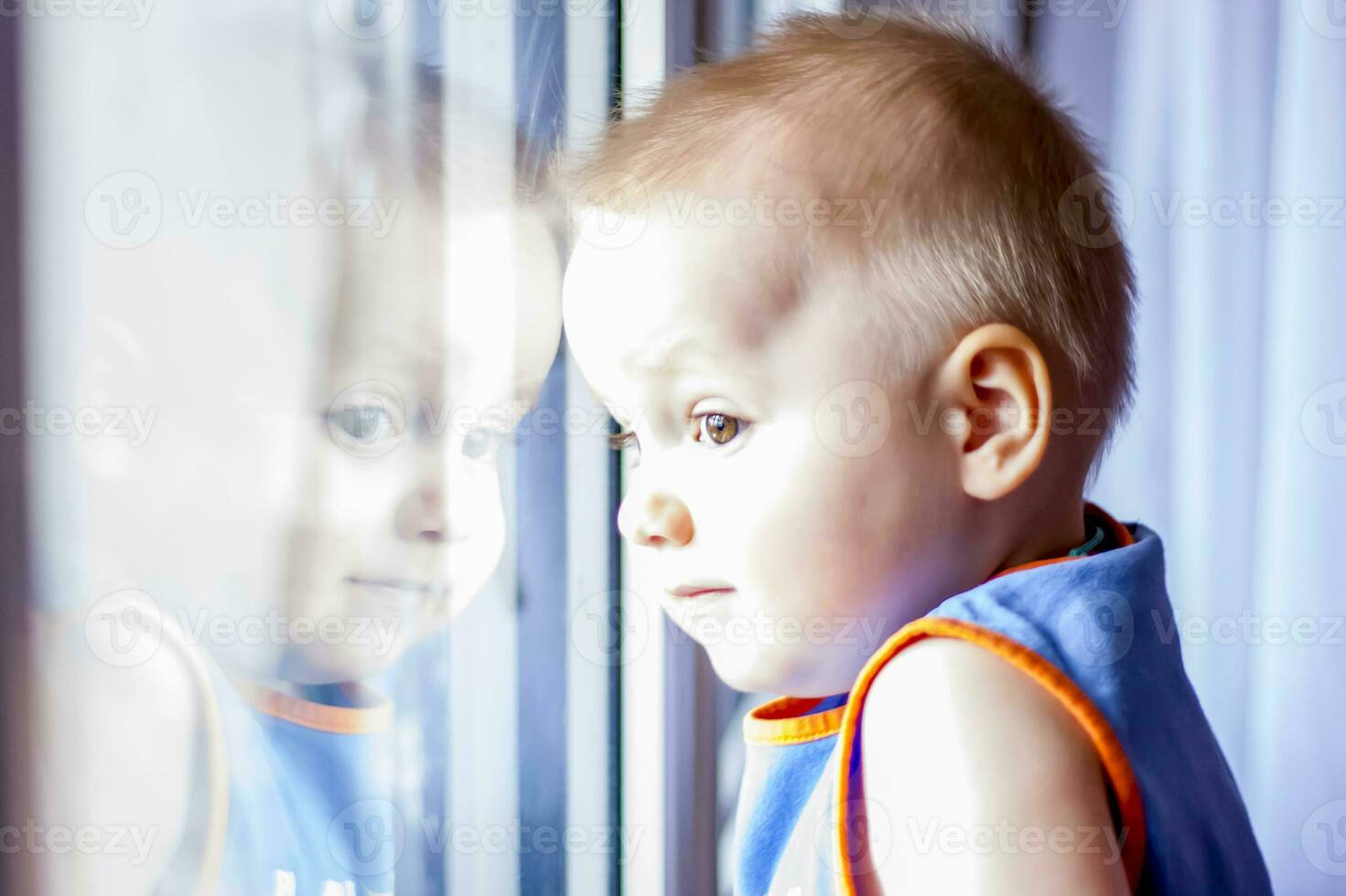 The child looks out the window. He really wants to walk. Because of the quarantine, everyone stays at home and doesn't go anywhere. photo
