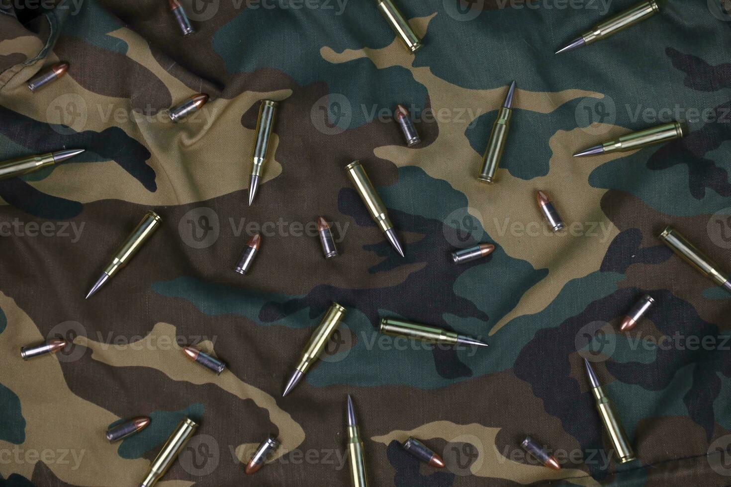 Many rifle bullets and cartridges on dark camouflage background photo
