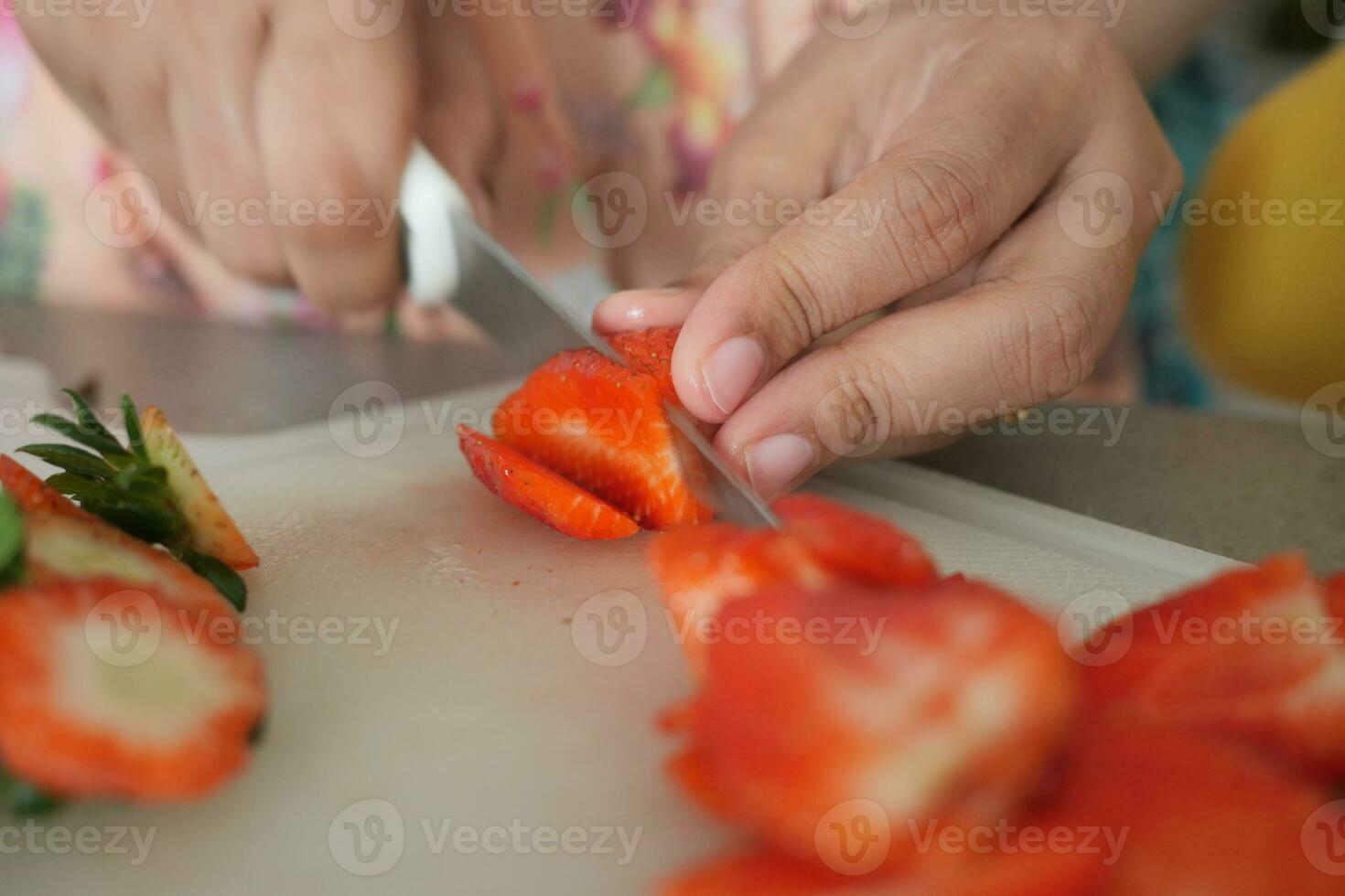 cutting Strawberries with knife on a chopping board on table photo