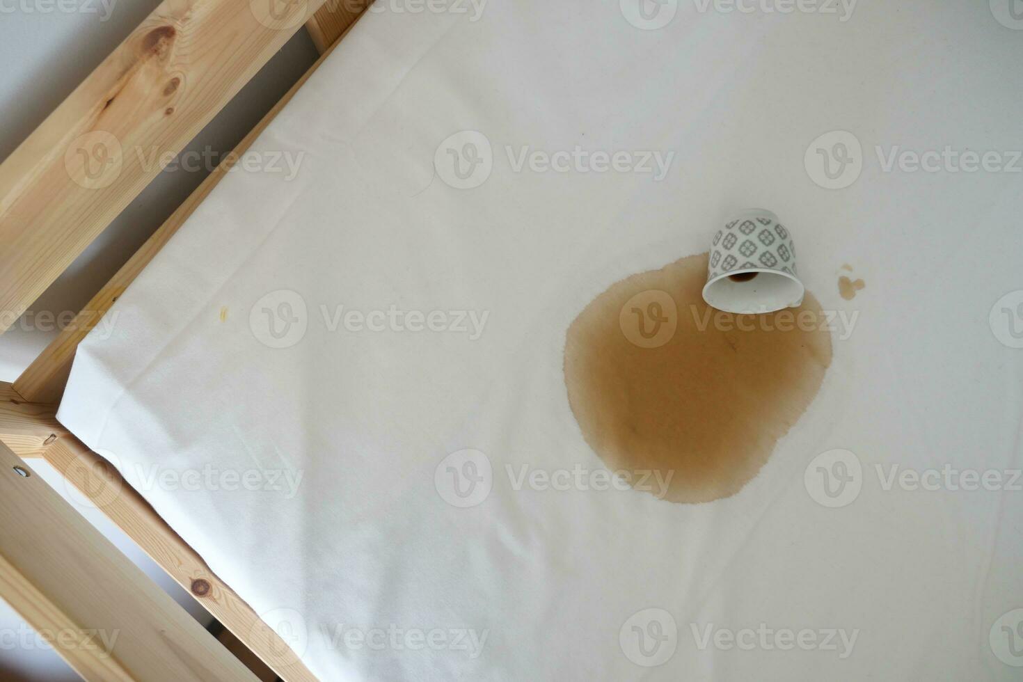 cup of coffee spilled on white color bed photo