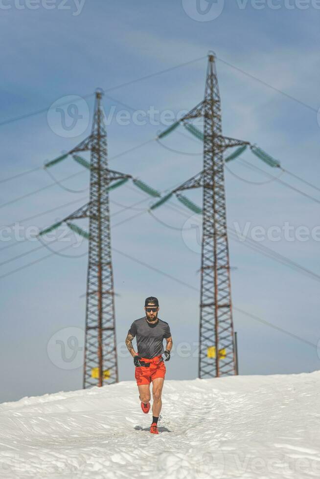 Athlete runs in the snow near high-voltage pylons photo