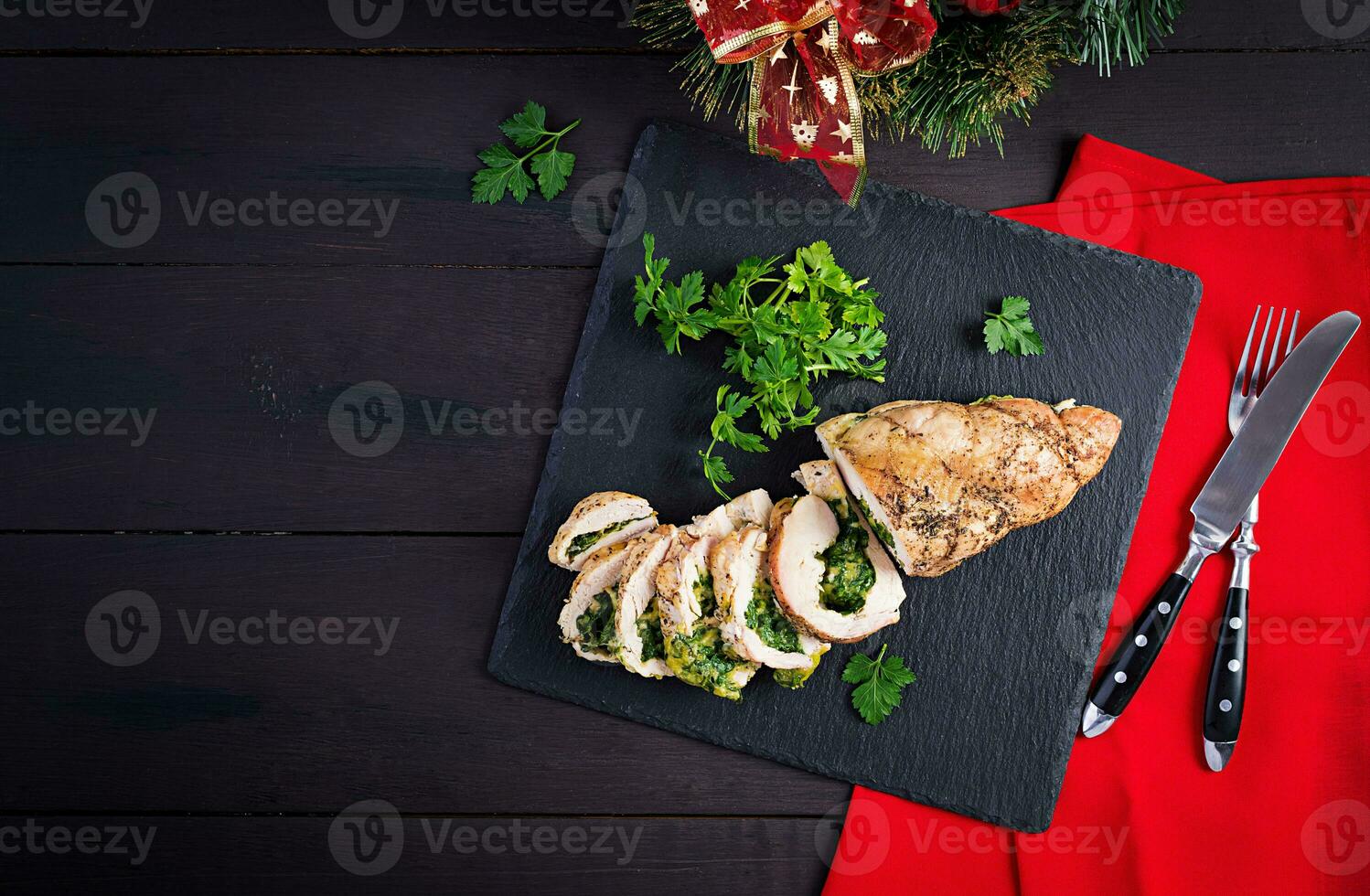 Roasted sliced Christmas roll of turkey with spinach and cheese on dark rustic background. Top view, copy space. Festival food. photo