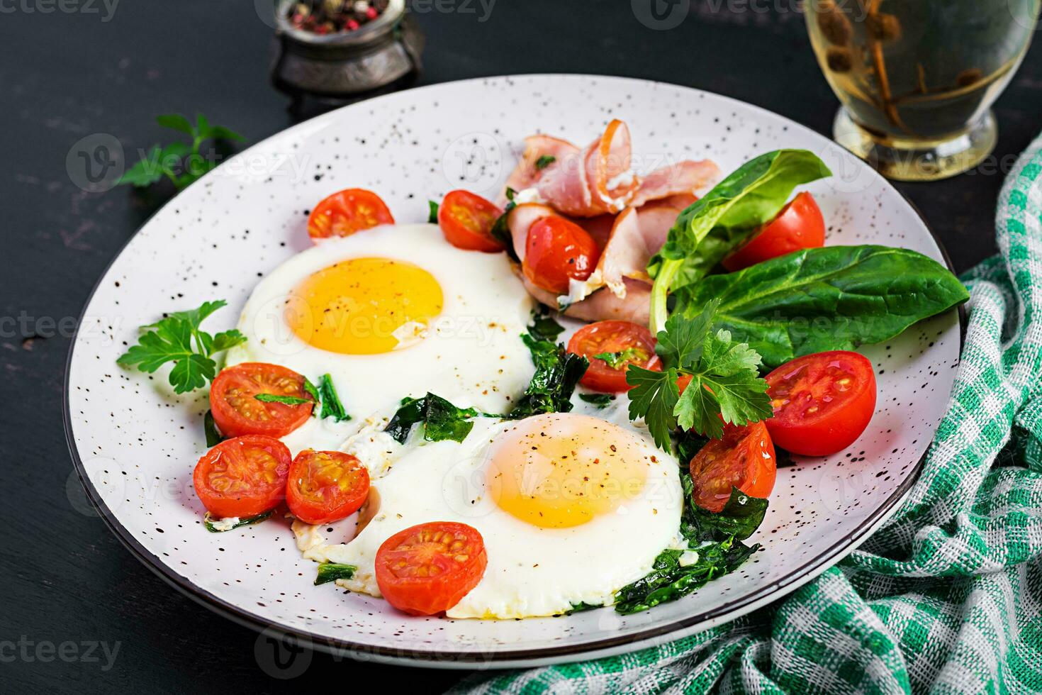 Plate with a keto diet food. Fried egg, ham, spinach, and tomatoes. Keto, paleo breakfast. photo