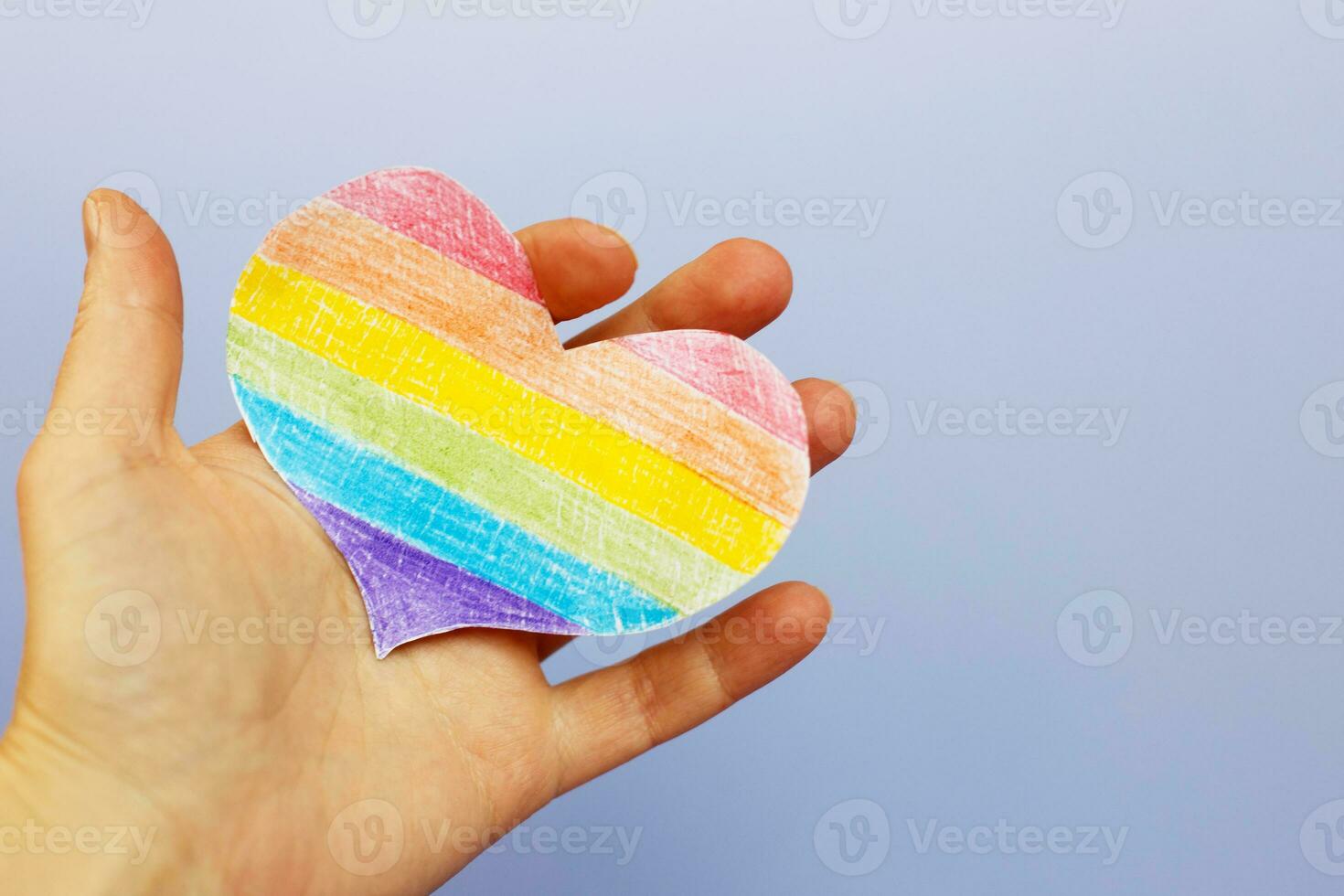 hands holding lgtb flag in the form of a heart on a purple backgroubd photo