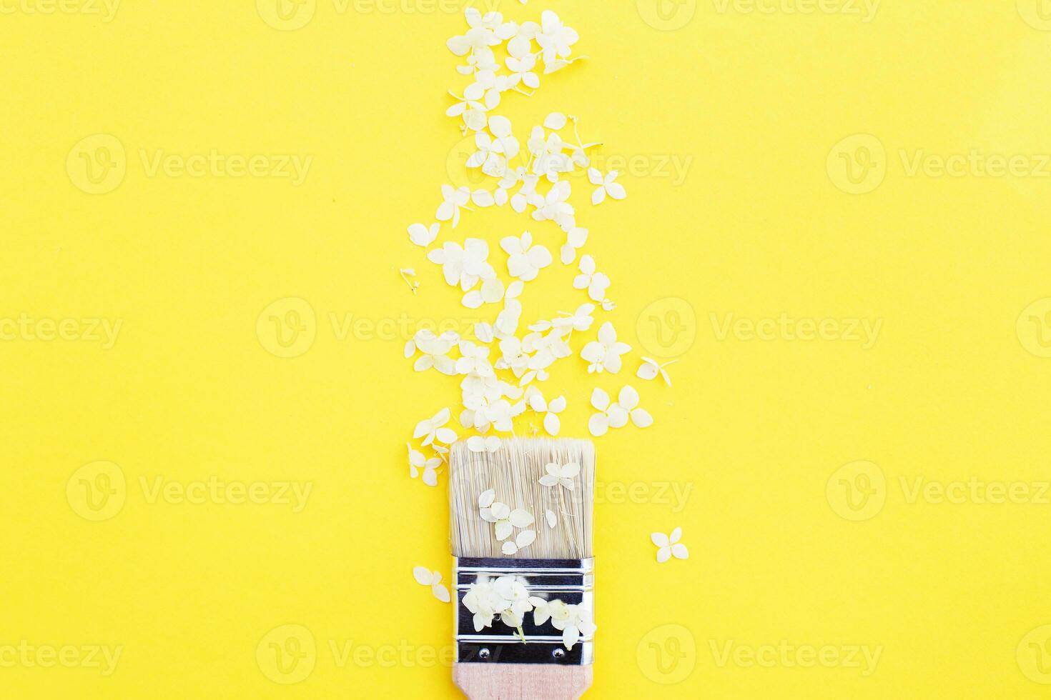 white hydrangea flowers and paint brush on a yellow background with copy space. photo