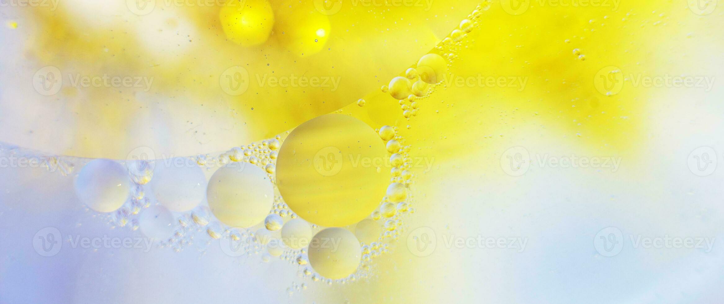 las burbujas de aceite de oro se cierran. círculos de agua macro. fondo amarillo y azul brillante abstracto. bandera foto