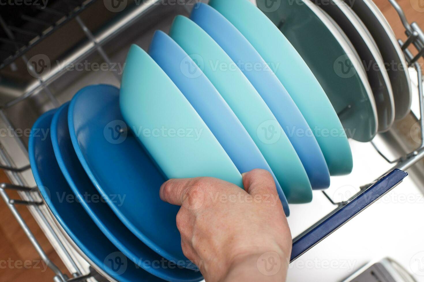 hand of a woman open dishwasher with clean dishes in the kitchen photo