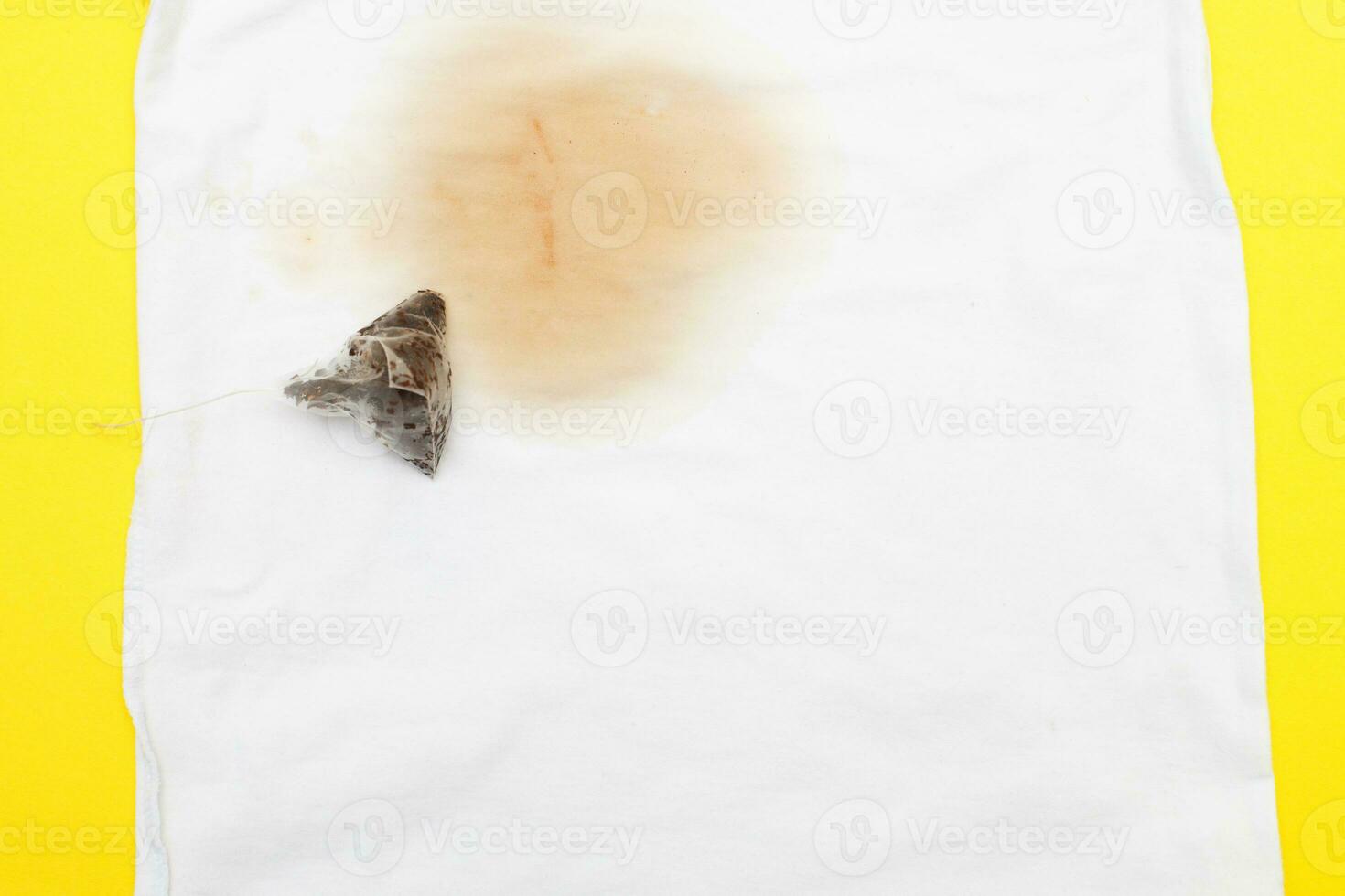 spilled tea stain on white clothes with a tea bag next to it photo