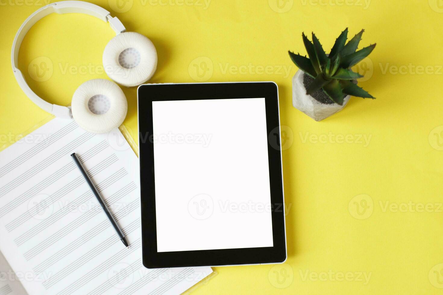 Top view open music book, headphones and a pen on a yellow background. mock up for music lessons photo