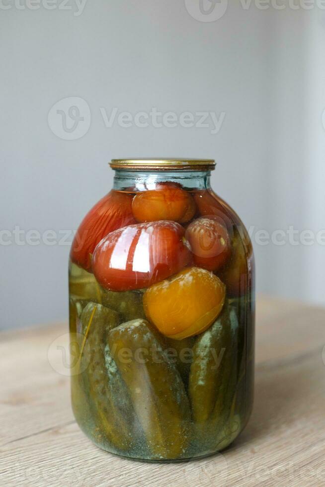spoiled can of vegetable seaming. Glass jar with homemade pickled tomatos and cucumbers with white fungus photo