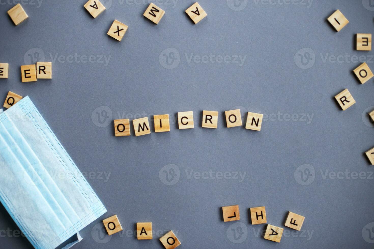 word omicron made by wooden blocks with medical mask on gray background. photo