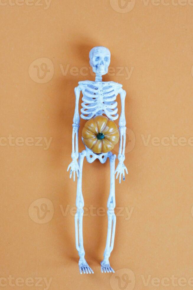 skeleton with pumpkin on orange background. halloween concept photo