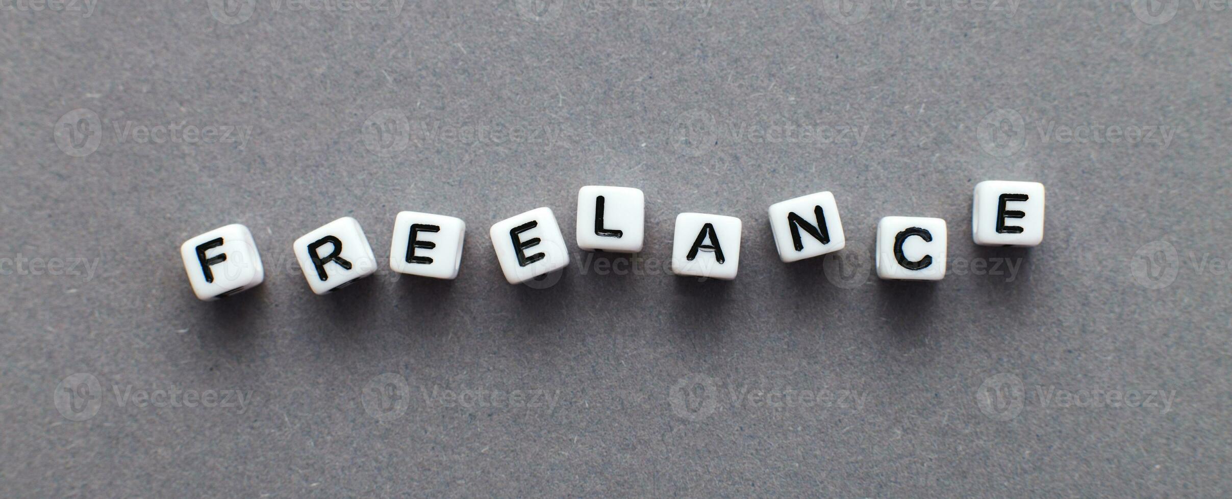 word freelance made from plastic cubes of beads on gray background. banner photo