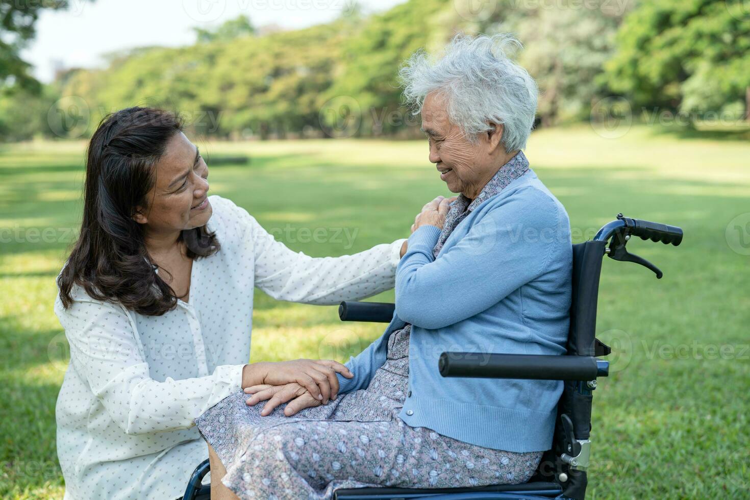 Caregiver help and care Asian elderly woman use walker with strong health while walking at park in happy fresh holiday. photo