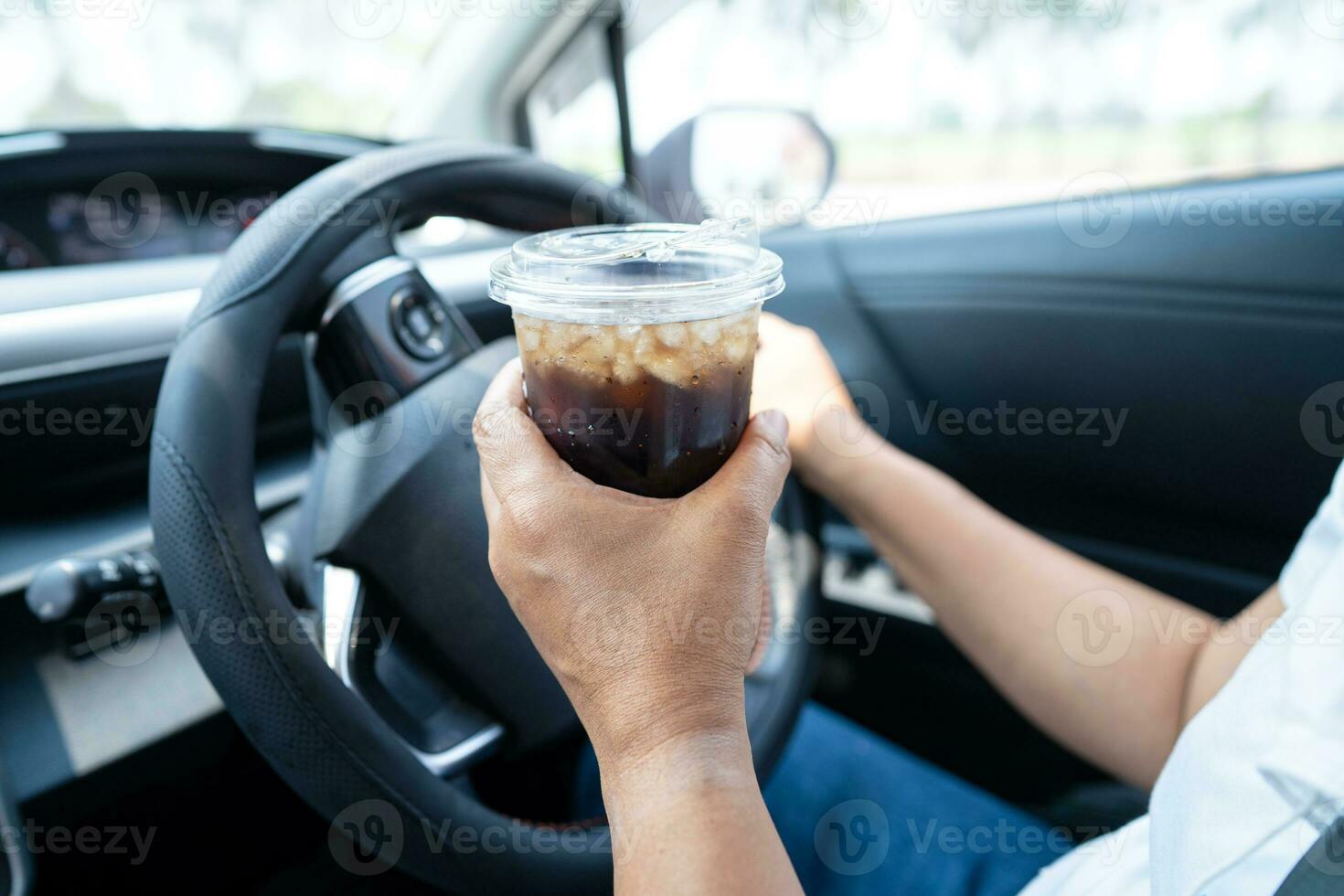 asiático mujer conductor participación taza para bebida agua mientras conducción un coche. el plastico caliente agua botella porque fuego. foto