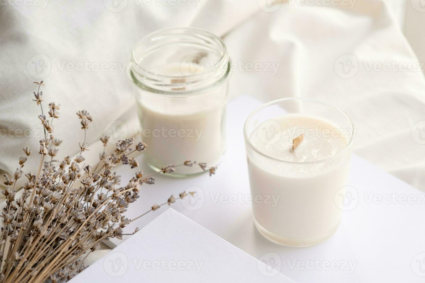 Soy wax aroma candles in jar on bed with lavender flowers. Candle mockup design photo