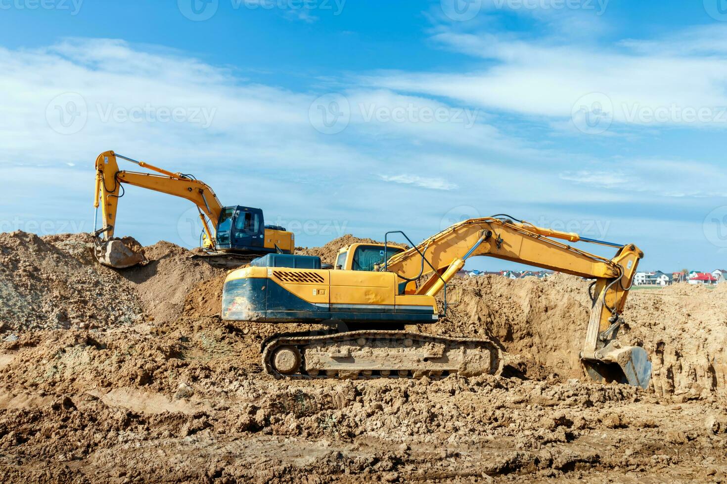 Two Excavator are digging soil in the construction site on sky background,with white fluffy cloud photo