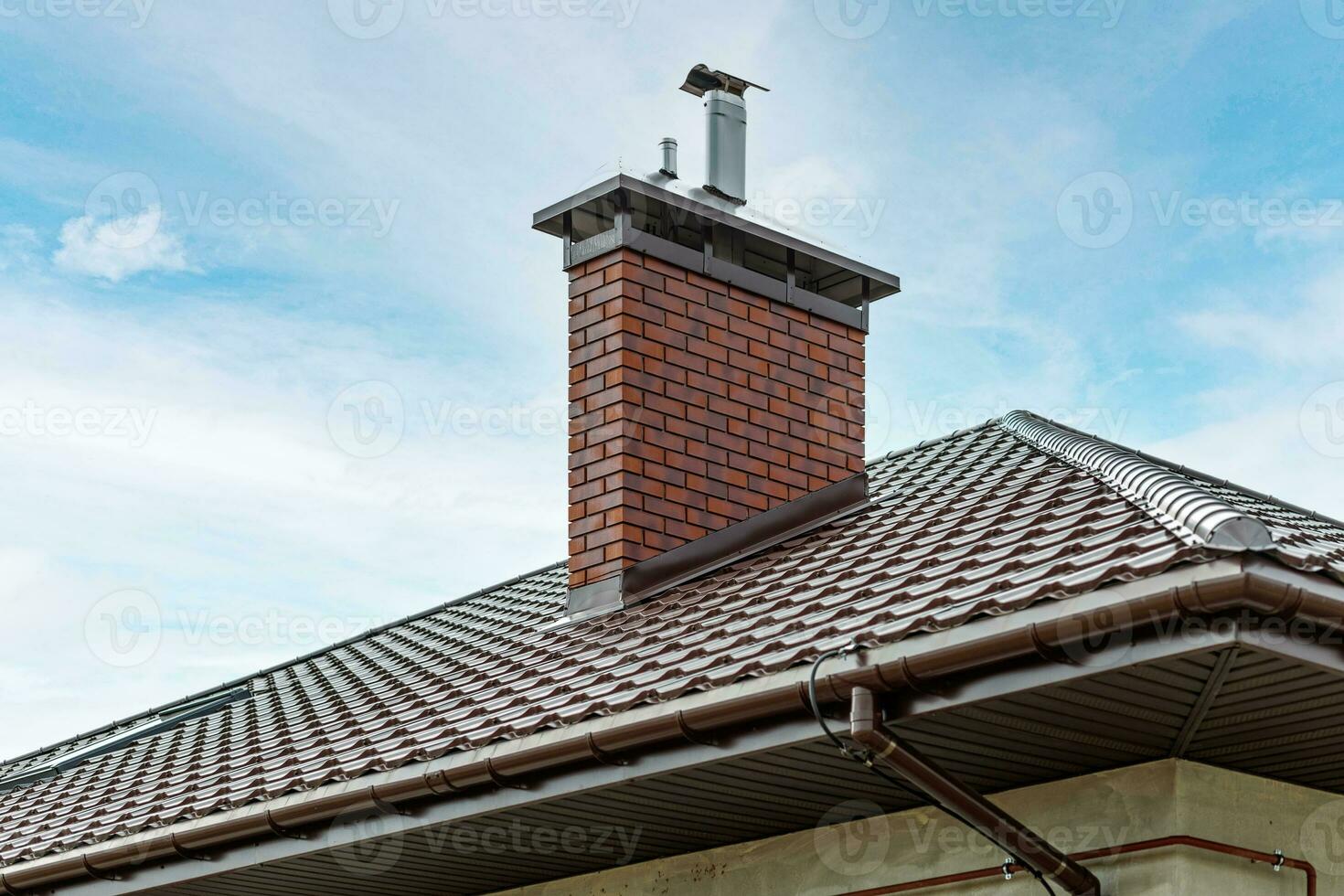 A chimney or ventilation pipe in a private house made of decorative bricks on the roof photo