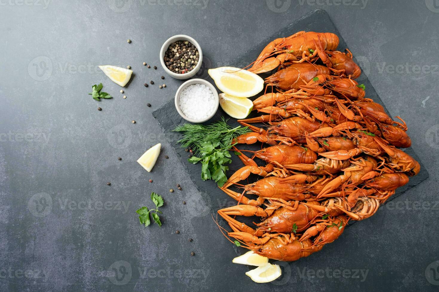 top view of cooked crawfish with lemons and spices on dark cement background photo