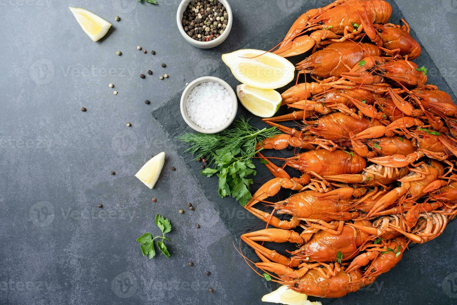 top view of cooked crawfish with lemons and spices on dark cement background photo