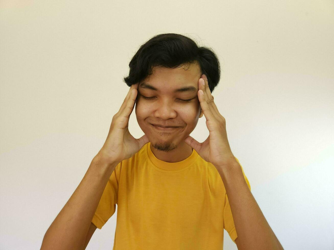 asian man holding his head, studio portrait of painful and headache man. Thinking gesture photo