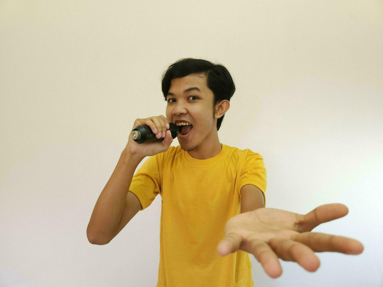 Portrait of young handsome Asian man singing a song with a microphone. happy and relax, enjoy the moment photo